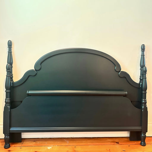 Dark Green wooden bed frame with spindle design against a white wall.